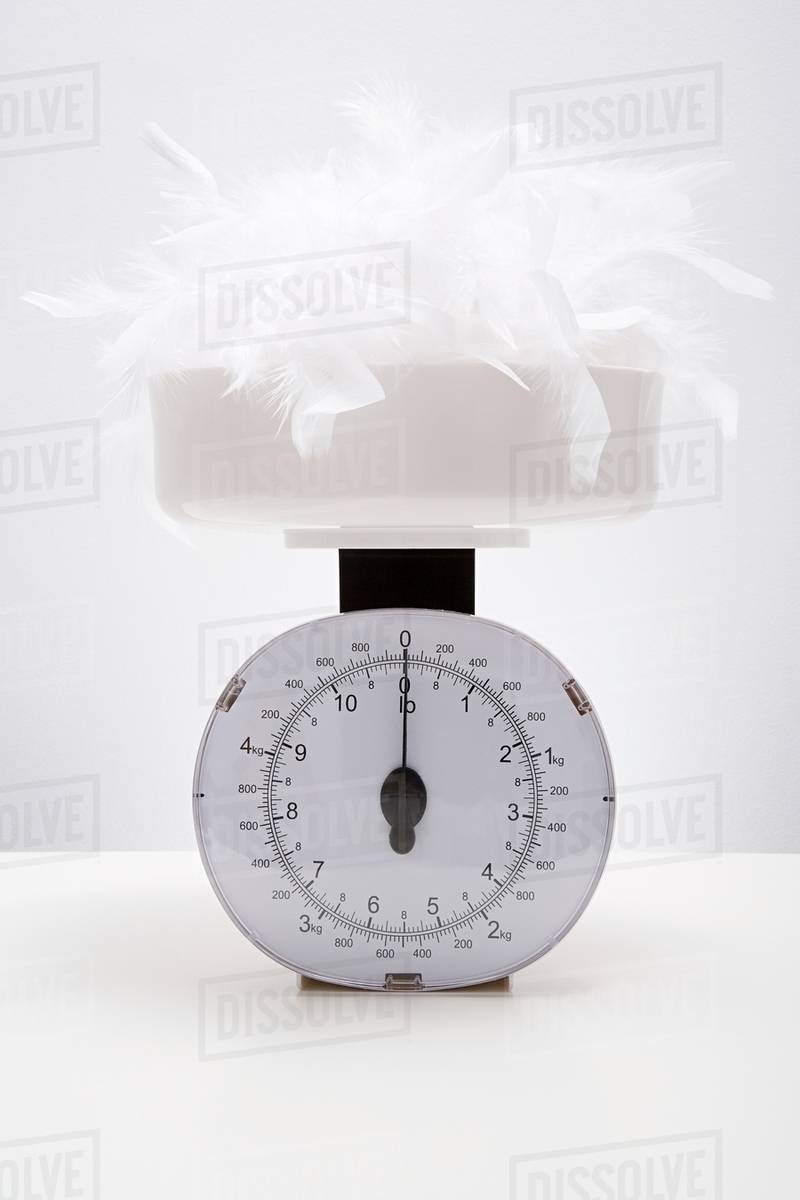Feathers on a weight scales Stock Photo Dissolve