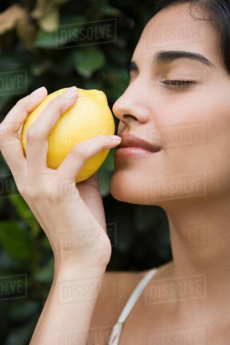 Woman smelling a lemon Stock Photo Dissolve