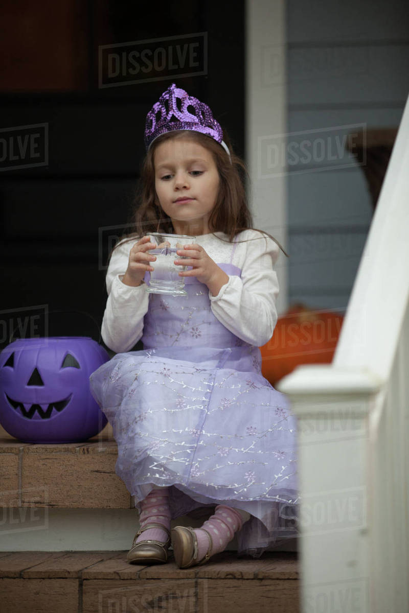 Girl trick or treating in fairy costume sitting on stairway drinking lemonade Royalty-free stock photo