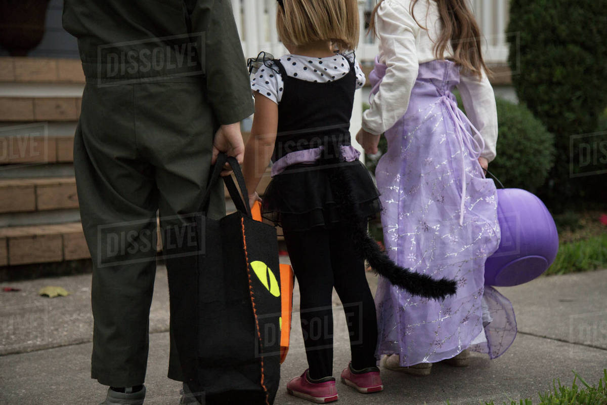 Boy and sisters trick or treating waiting at porch stairway Royalty-free stock photo