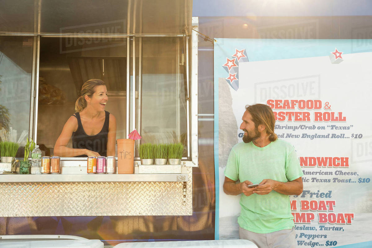 Man standing beside fast food trailer speaking to woman inside trailer Royalty-free stock photo