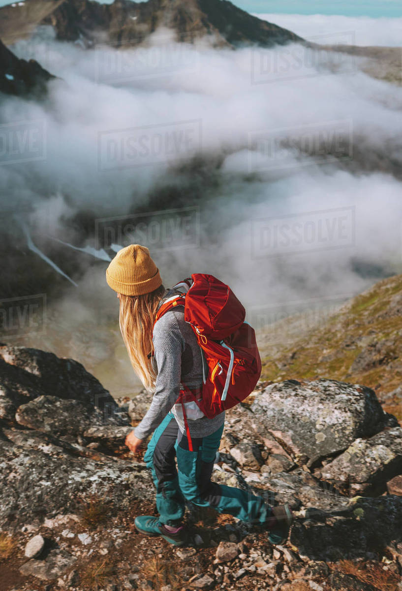 Woman hiking in mountains with red backpack travel trail running activity summer vacations healthy lifestyle outdoor adventure solo trekking in Norway Royalty-free stock photo
