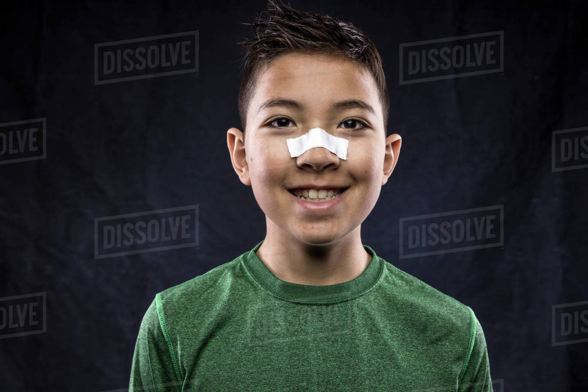A close up portraiture of a confident athletic boy who has tape on his