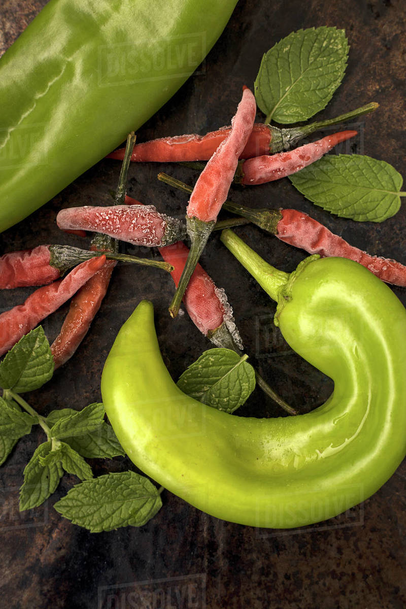 An overhead shot of assorted peppers and peppermint leaves. Stock Photo Dissolve