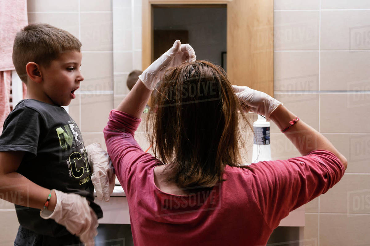 Mother preparing to dye her hair with the help of her children. concept of staying home and doing chores with the children during the coronavirus quarantine Royalty-free stock photo