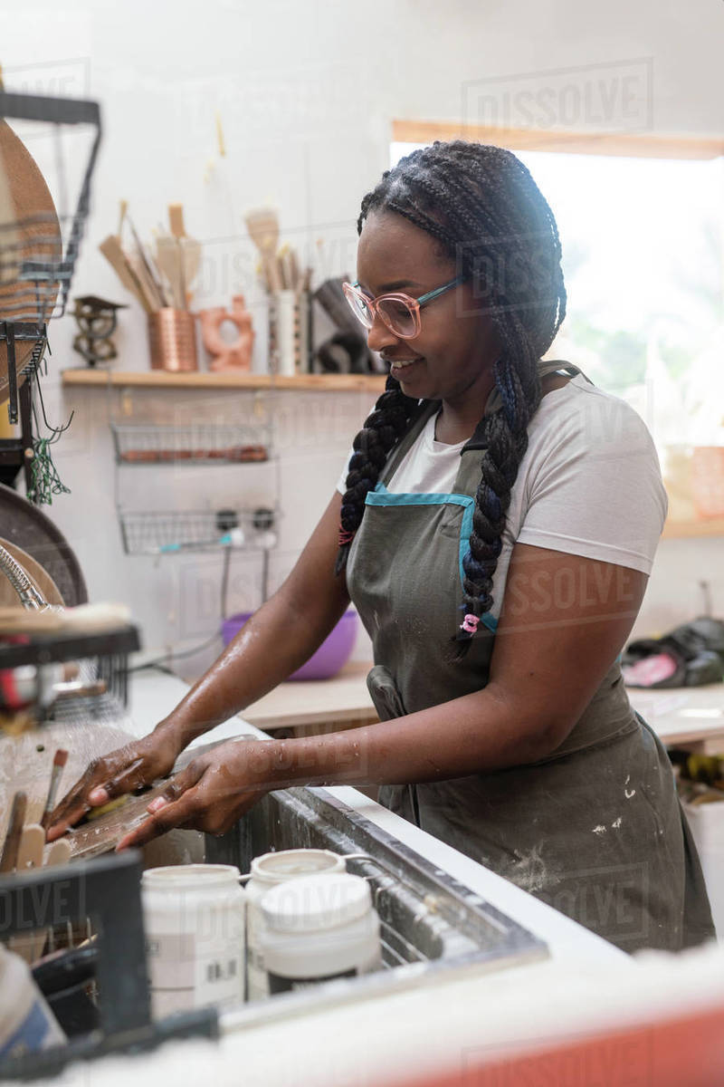 Woman washing her pottery at the ceramics studio Stock Photo Dissolve