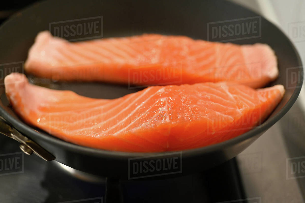 Two pieces of Tasmanian salmon steak fillet cooking in a fry pan. Stock Photo Dissolve