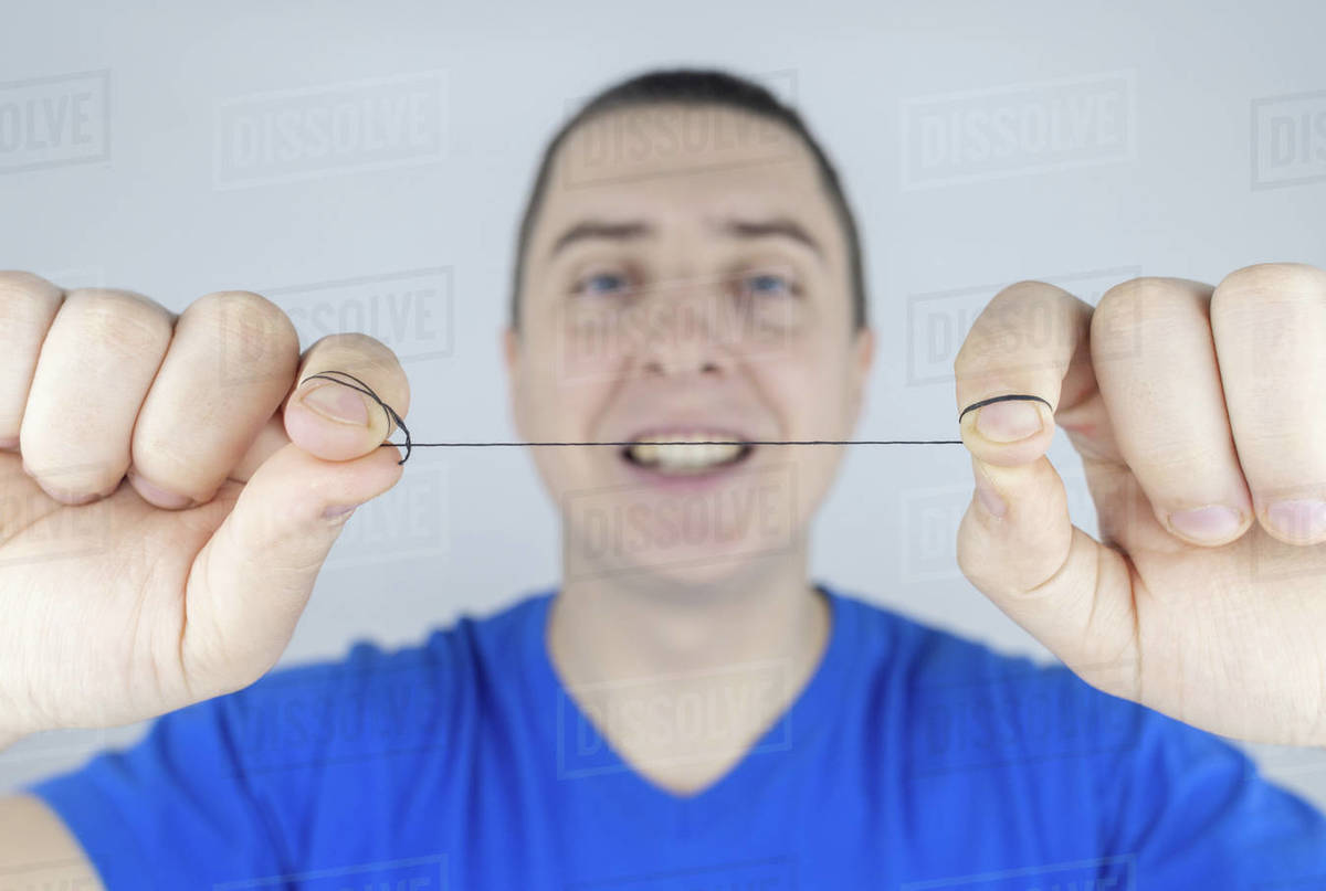 Dental floss close up. A man in front of a mirror brushes his teeth