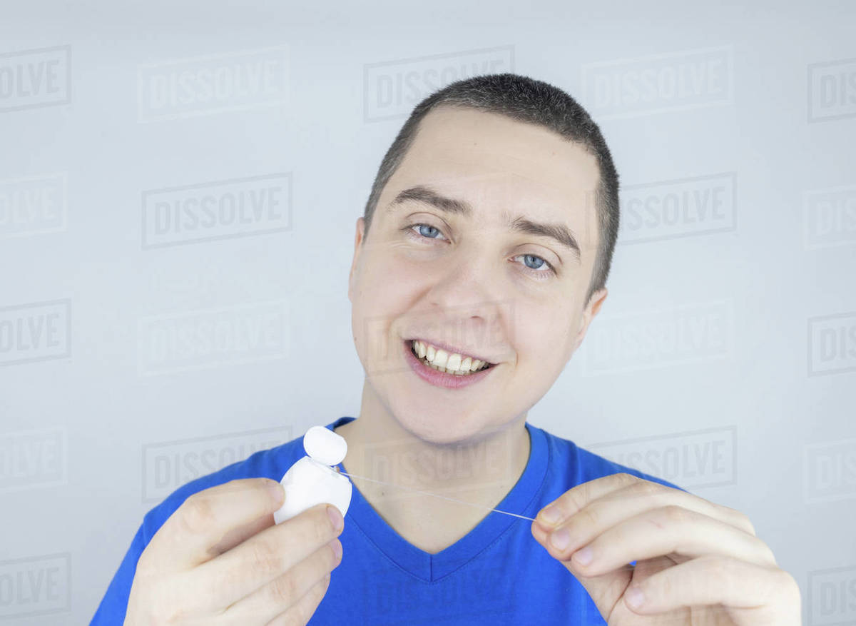 Dental floss close up. A man in front of a mirror brushes his teeth