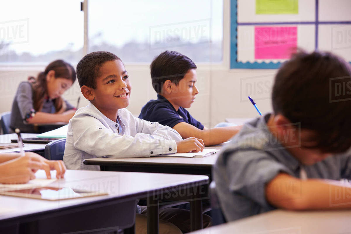 Elementary school kids working at their desks in a classroom Stock