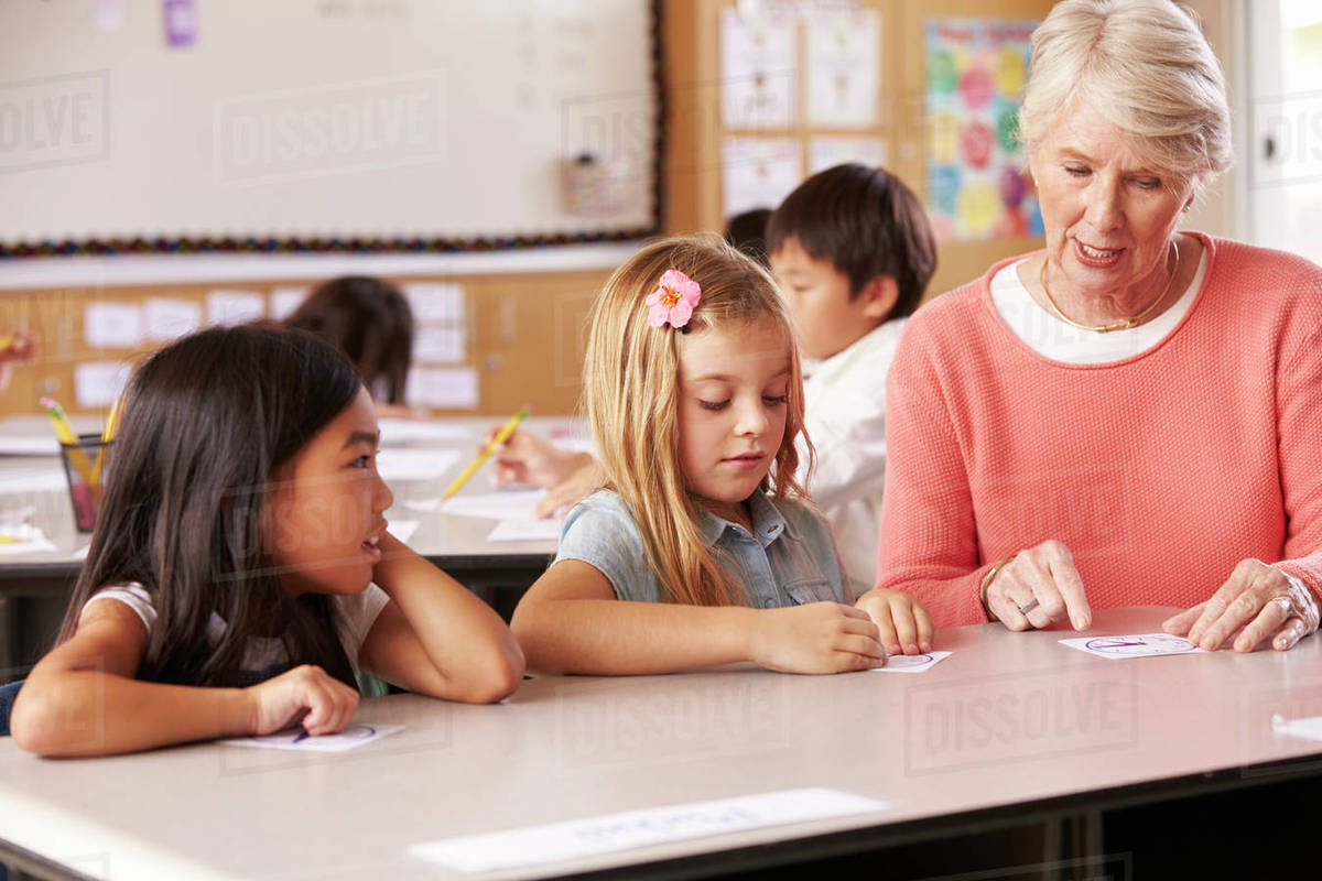 Senior teacher helping pupils in elementary school lesson Royalty-free stock photo