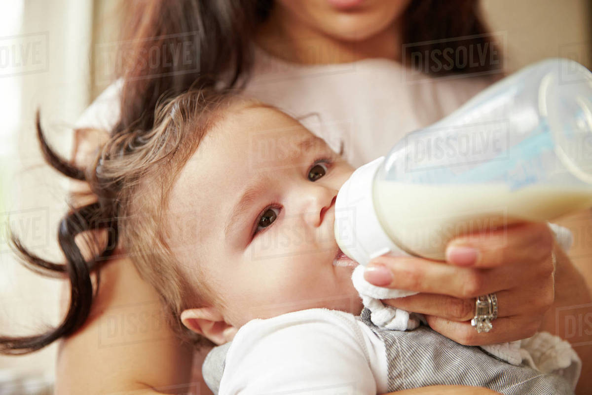 Mother feeding baby boy from bottle at home Royalty-free Stock