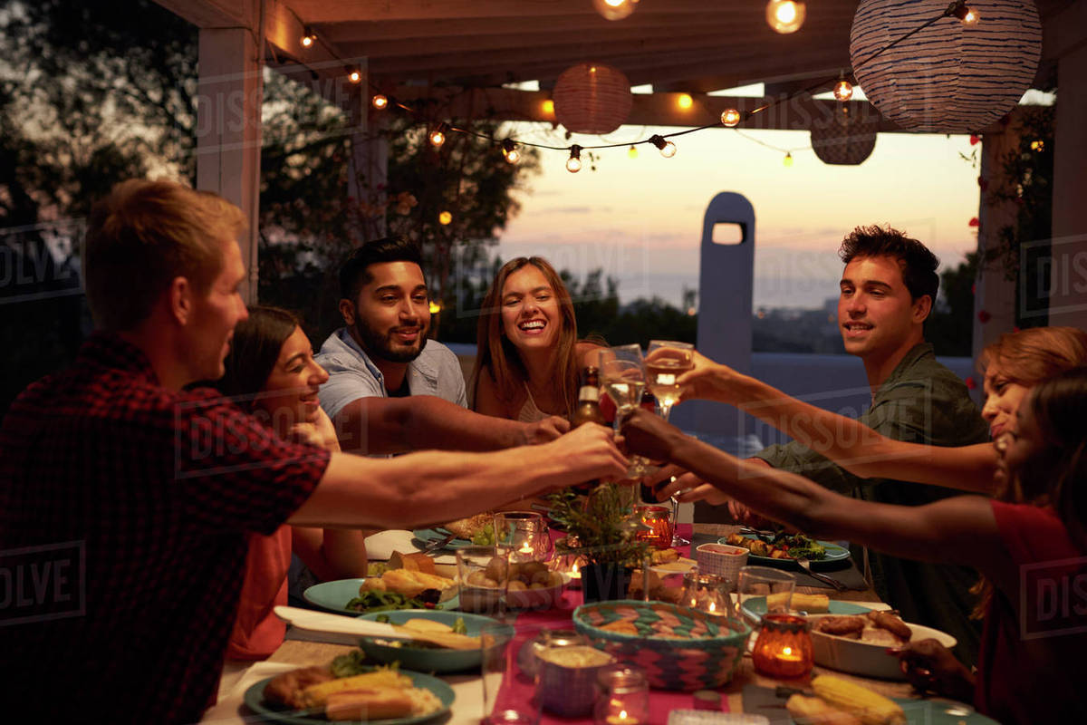 Friends make a toast at a dinner party on a patio, close up Stock
