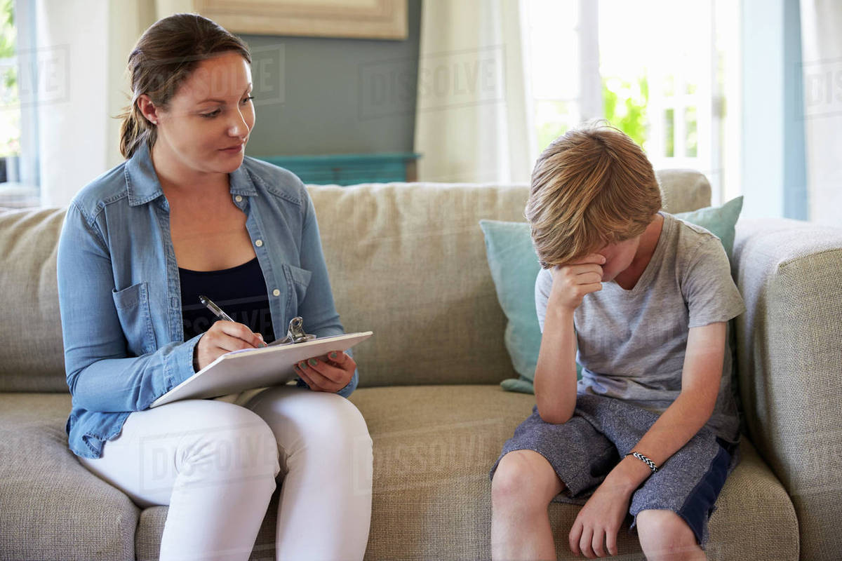 Young boy with problems talking with counselor at home Stock Photo