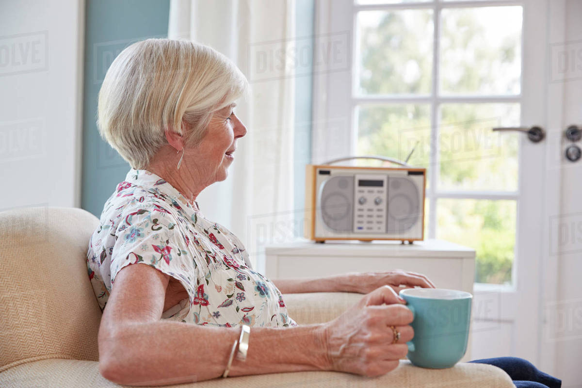 Senior woman drinking tea and listening to radio at home Stock Photo