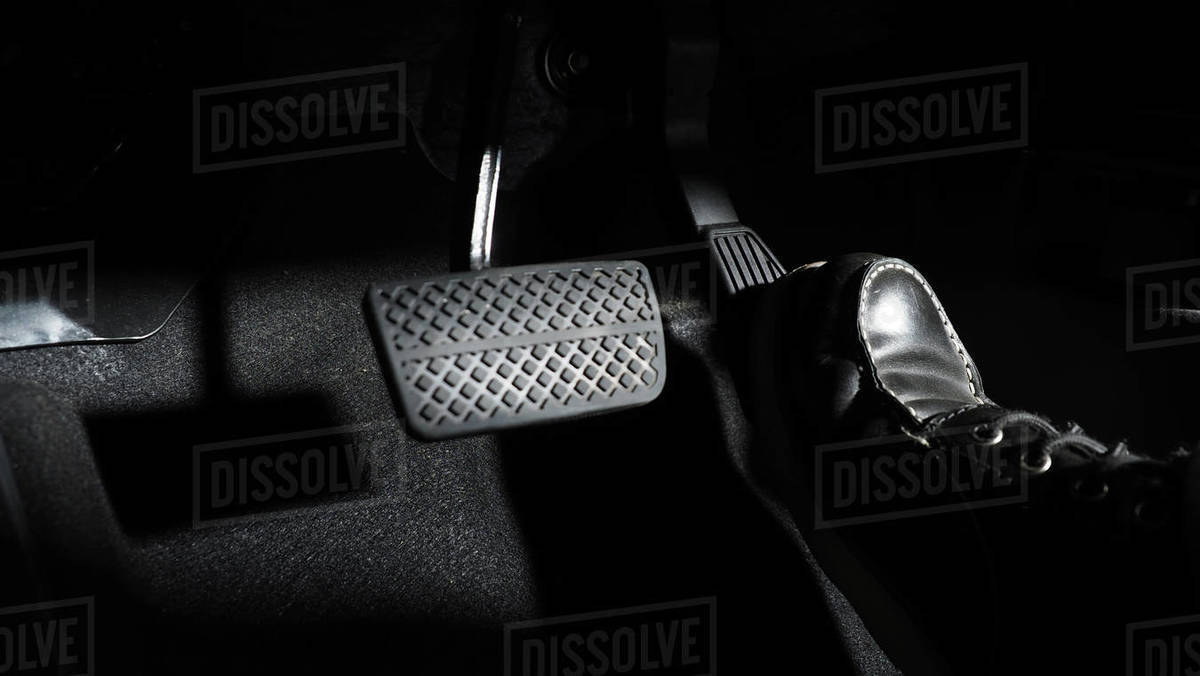 Accelerate and Brake. Foot pressing foot pedal of a car to drive ahead