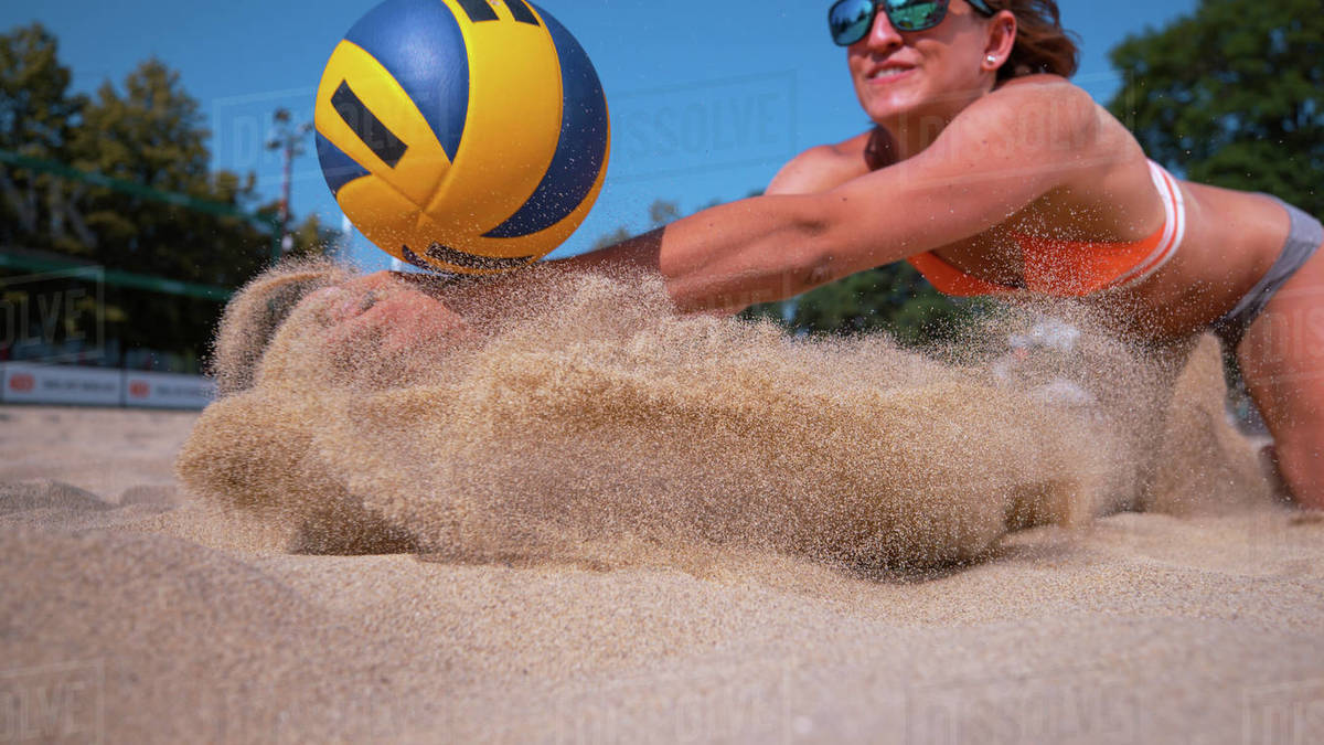 CLOSE UP, DOF Smiling Caucasian female volleyball player dives and
