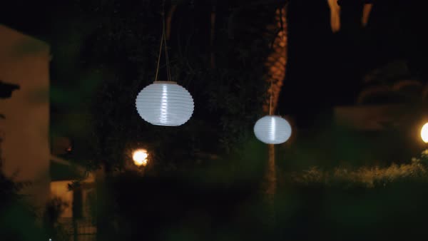 House Garden At Night With White Chinese Paper Lanterns Hanging In House Garden At Night With White Chinese Paper Lanterns Hanging In The Trees And Illuminating Darkness