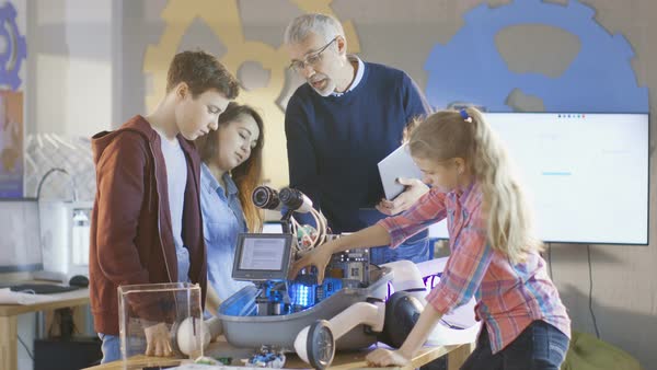 Teacher and his pupils work on a programable robot with led ...