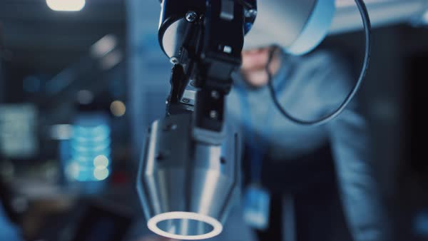 Close up of a futuristic robotic arm moving a metal object and placing ...