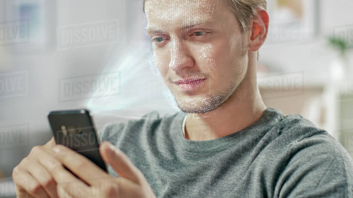 Young man identified by biometric facial recognition scanning process from his smartphone. Futuristic concept: projector identifies individual by illuminating face by dots and scanning with laser Royalty-free stock photo