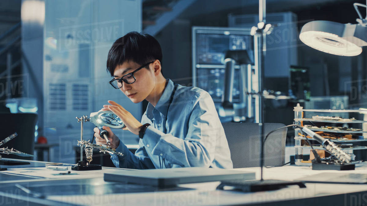 Professional Japanese Electronics Development Engineer in Blue Shirt is Soldering a Circuit
