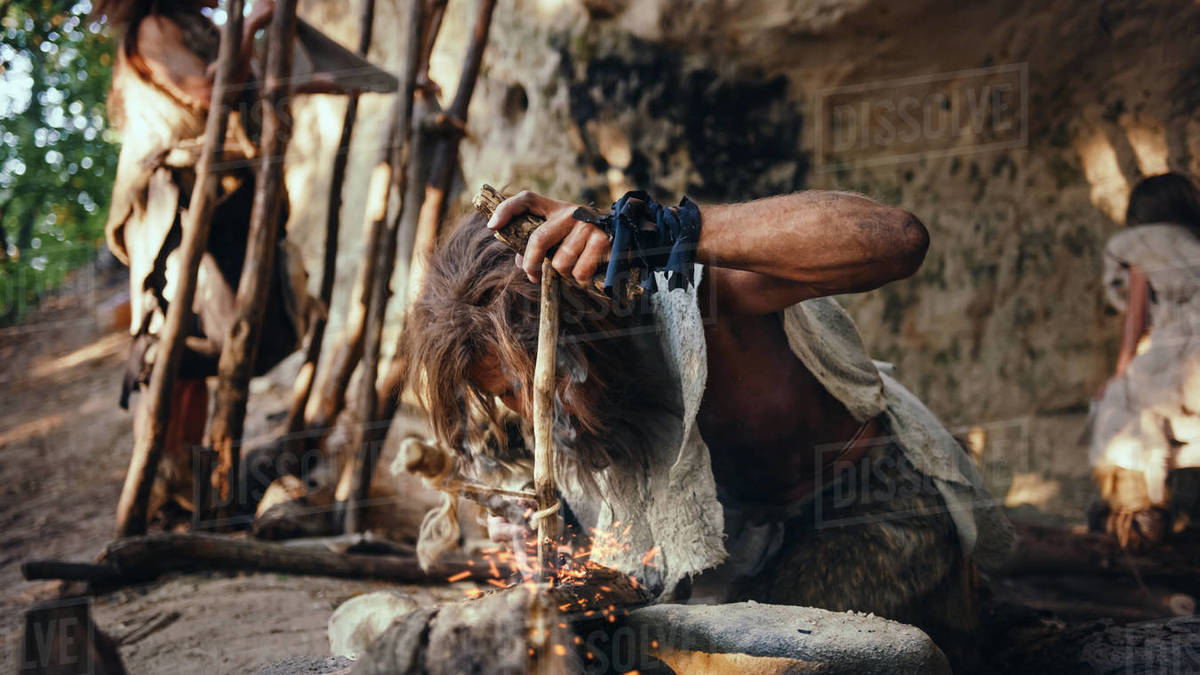 Primeval Caveman Wearing Animal Skin Trying to make a Fire with Bow