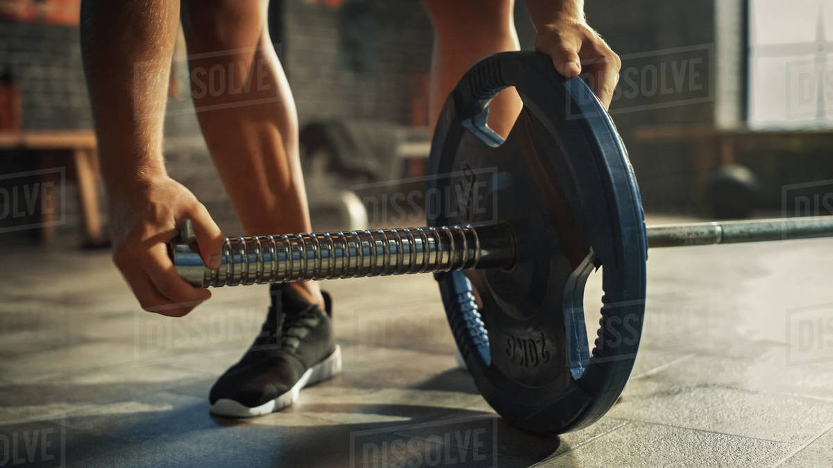 Closeup Shot of Bodybuilder Puts Additional Weights on a Barbell