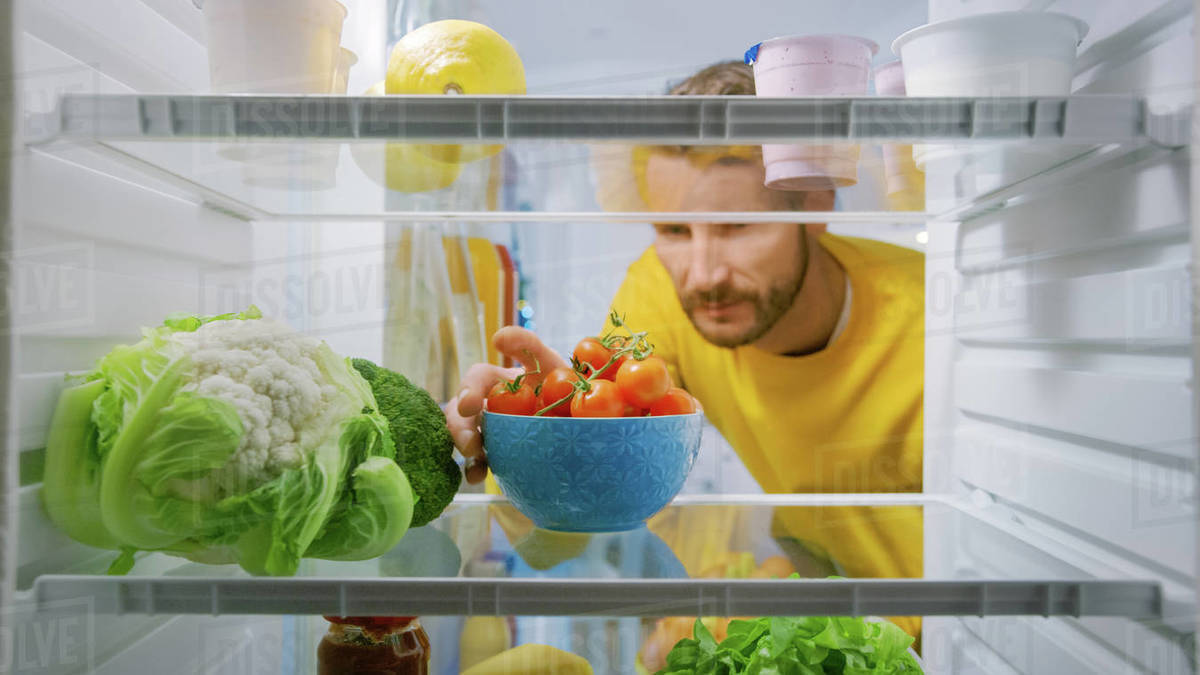 Inside Kitchen Fridge Handsome Man Takes Cherry Tomatoes from Opened Fridge. Man Preparing