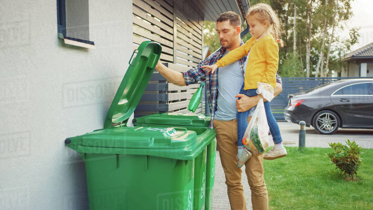 Man throwing away trash next to his house Stock Photo Dissolve