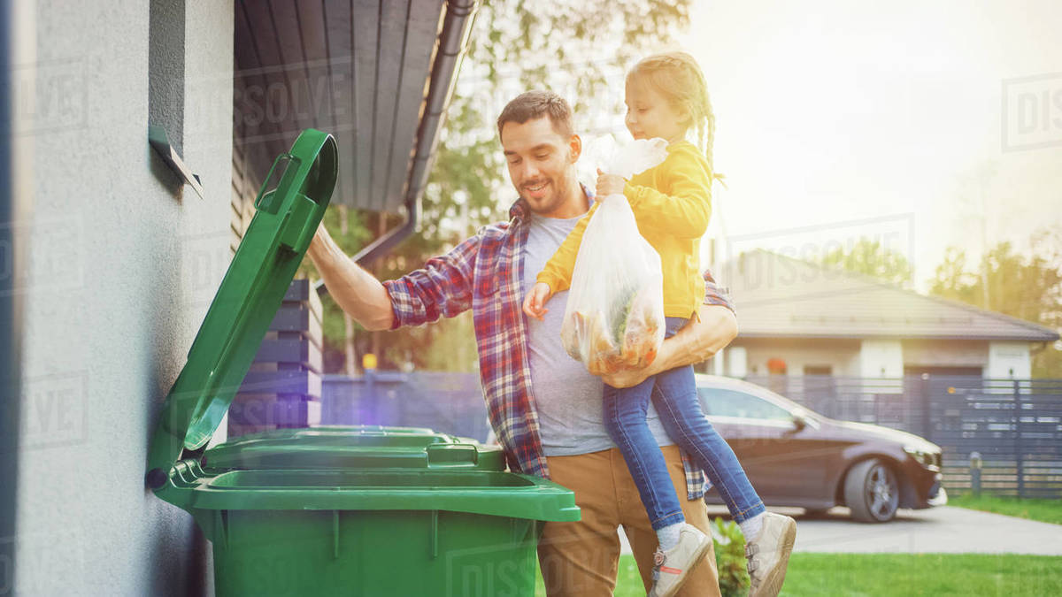 Man throwing away trash next to his house Stock Photo Dissolve