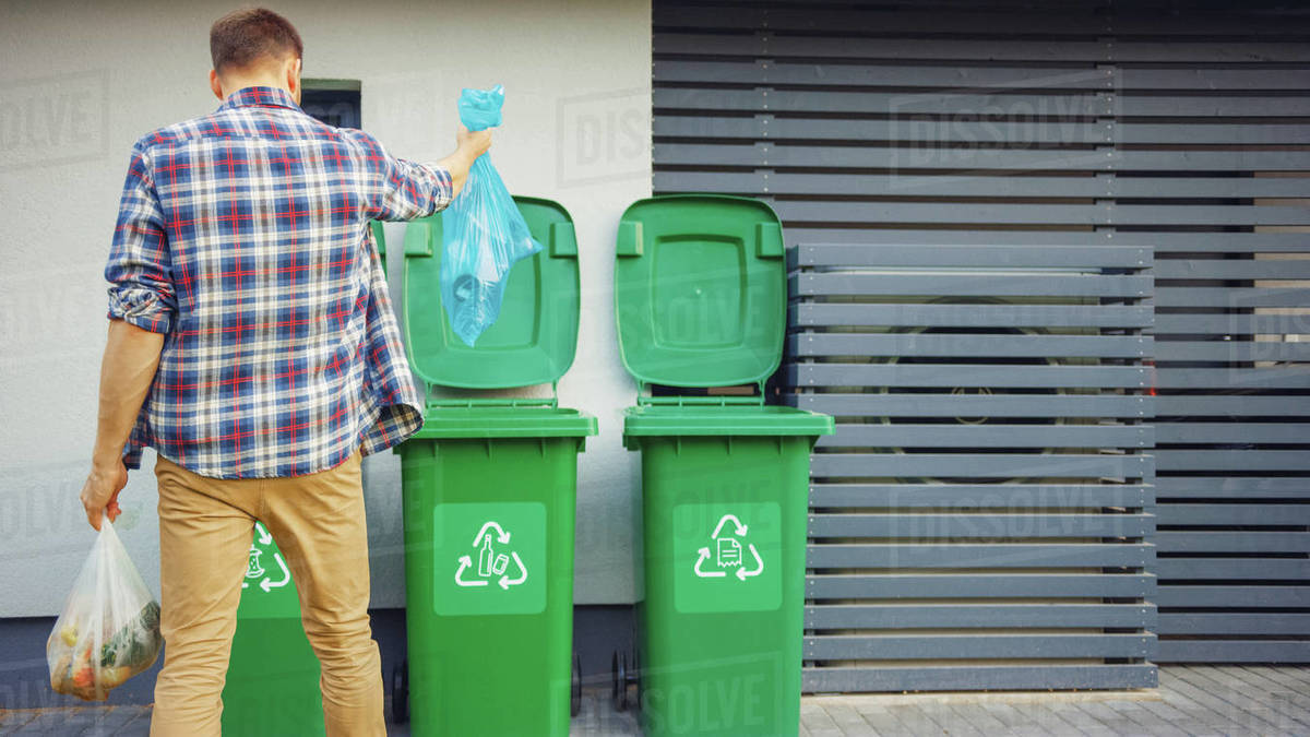 Man throwing away trash next to his house Stock Photo Dissolve