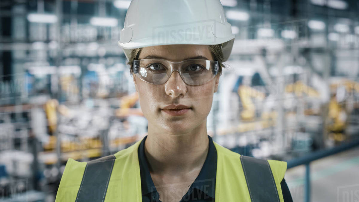 Portrait of Female Automotive Industry Engineer Putting on Safety Glasses at Car Factory