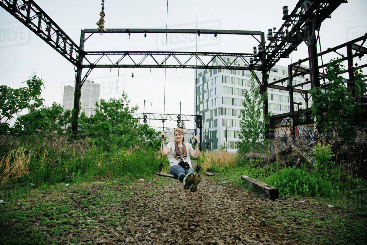 Woman swinging on swing at electricity substation Stock Photo Dissolve