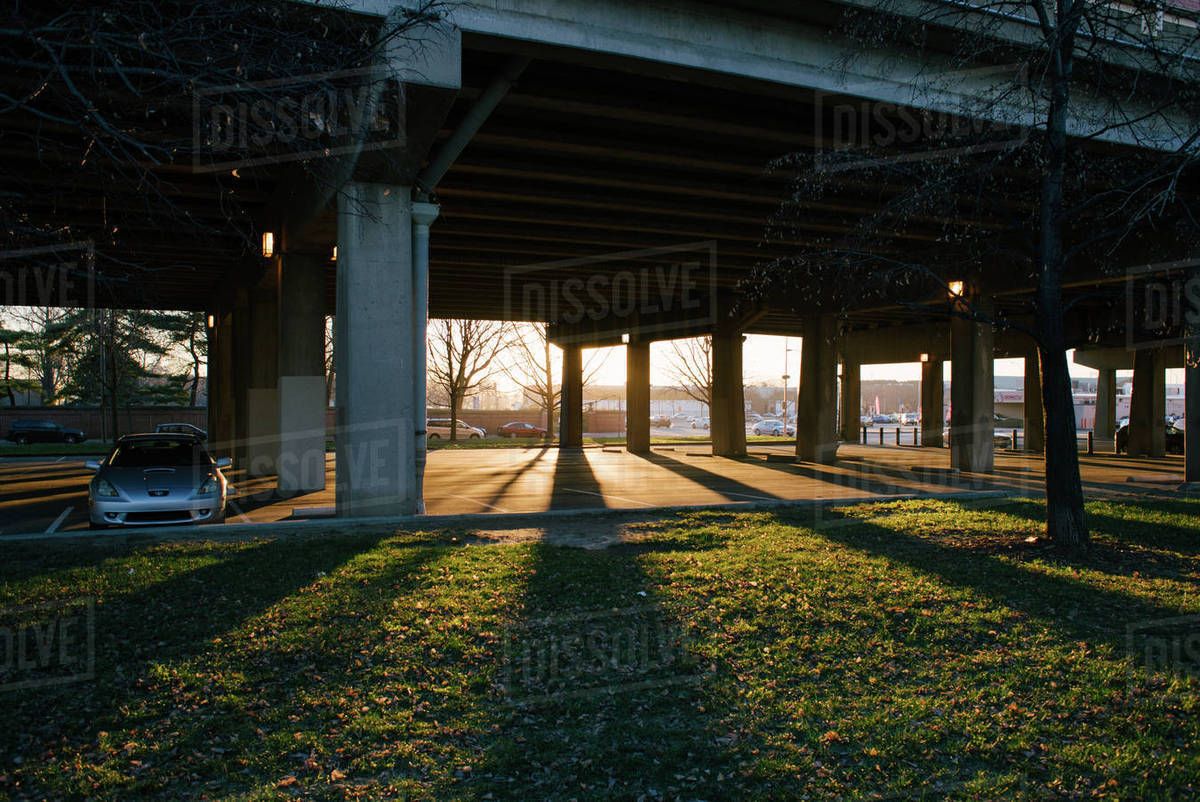 Sunlight over parking lot under bridge Stock Photo Dissolve