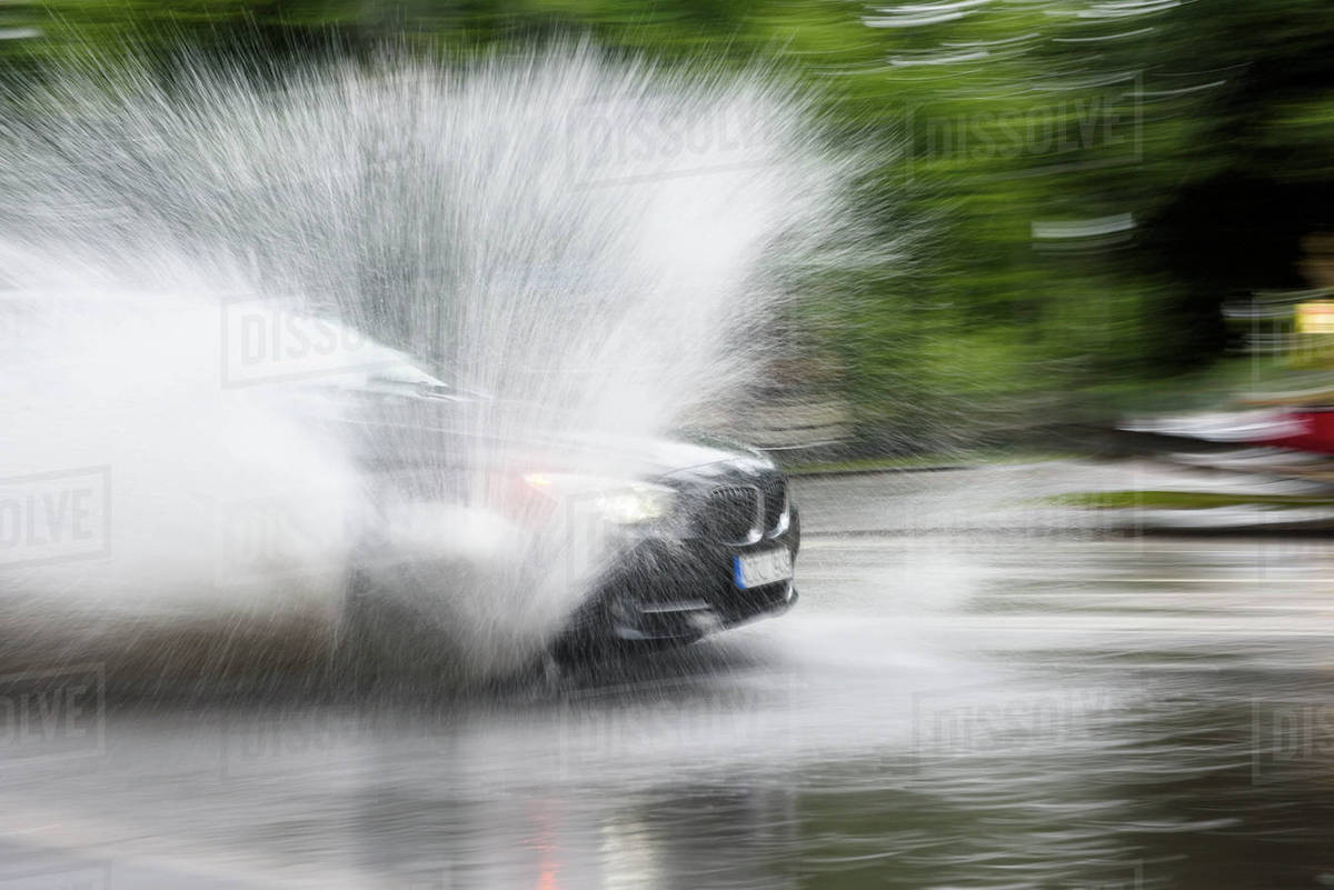 Car splashing water on road Stock Photo Dissolve