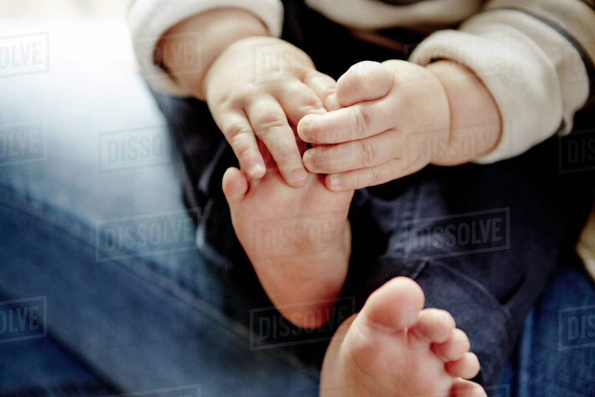 Babys hands holding feet Stock Photo Dissolve