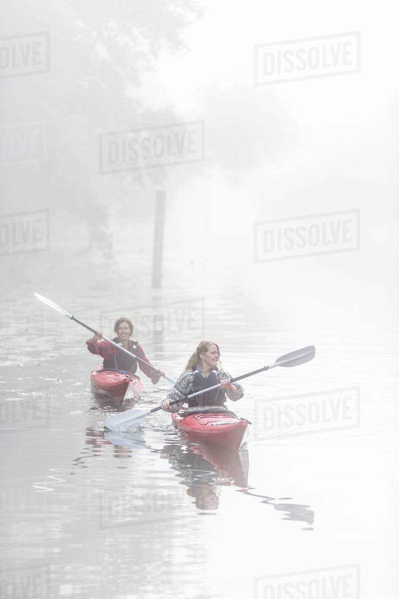 Women kayaking in fog Stock Photo Dissolve