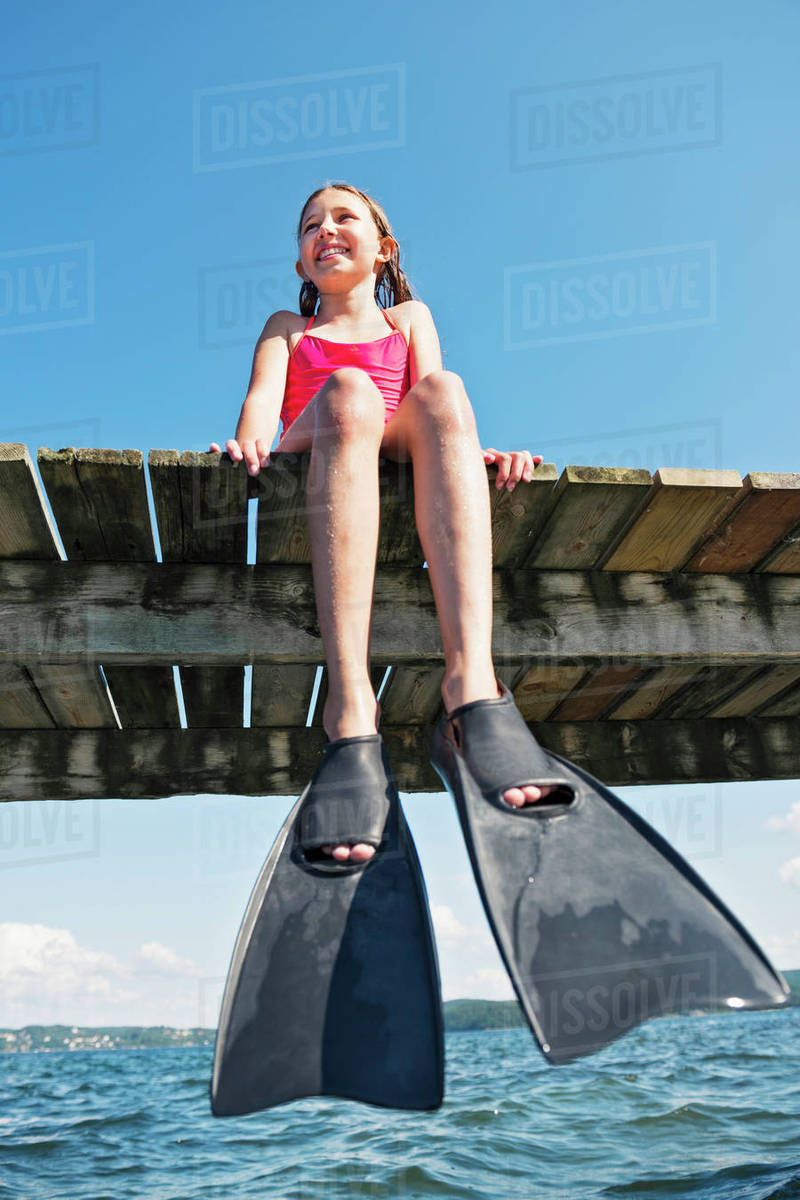 Girl wearing flippers on jetty Stock Photo Dissolve