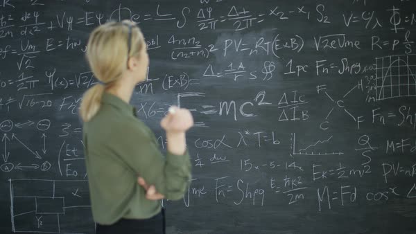 Portrait smiling academic woman in classroom studying math formulas on ...