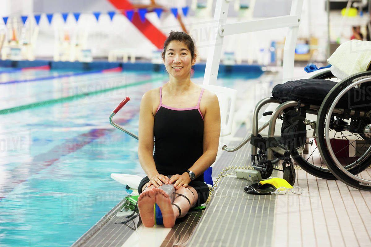 A Paraplegic Woman Sits At The Edge Of A Swimming Pool On A Lift Beside
