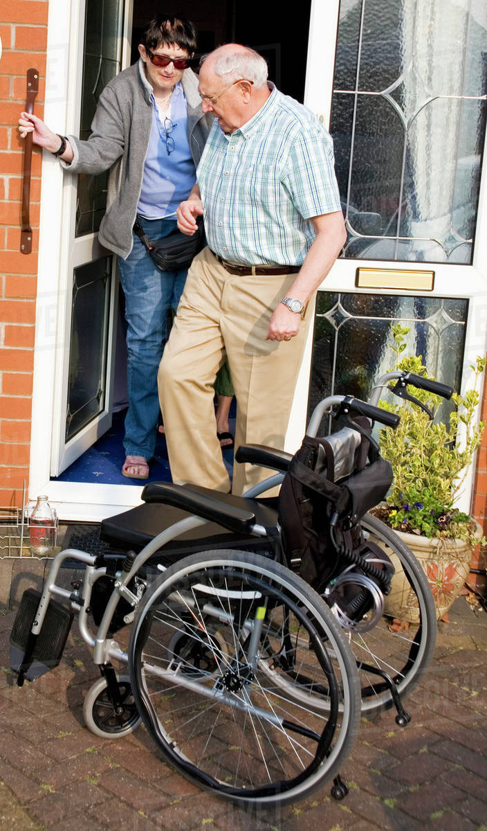Two Friends Helping Each Other Get Out Of The Door To Wheelchair
