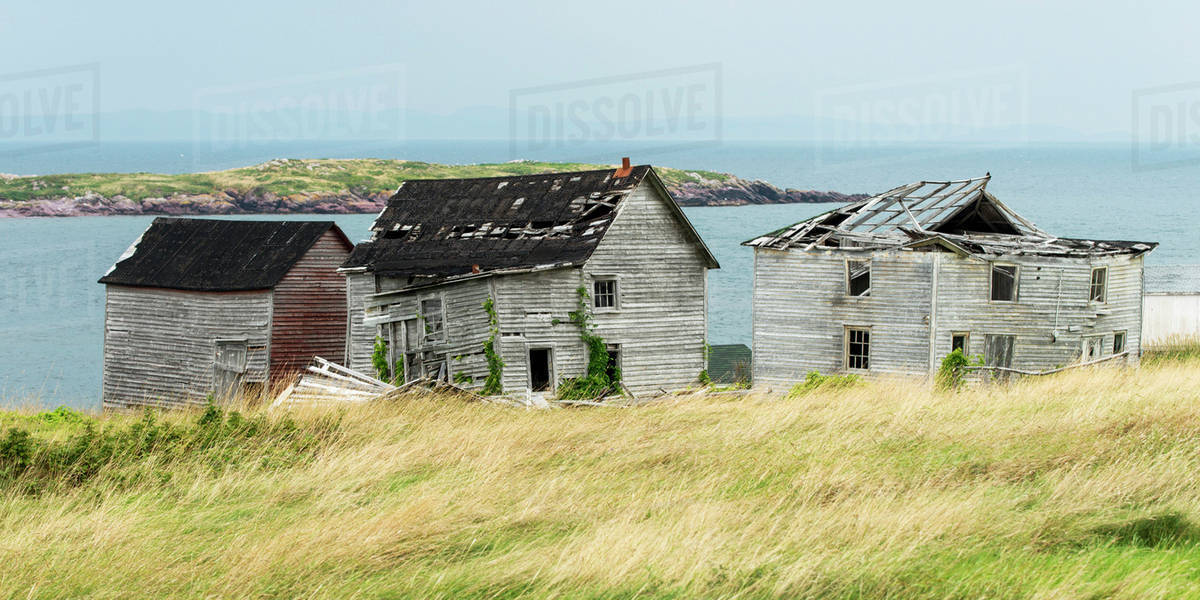 Broken and abandoned wooden houses along the water's edge of the