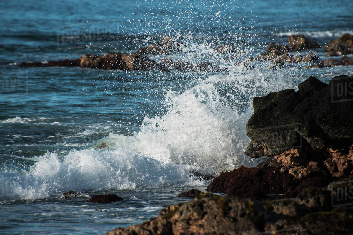 Surf breaks on the rugged rocks along the shore; Poipu, Kauai, Hawaii, United States of America