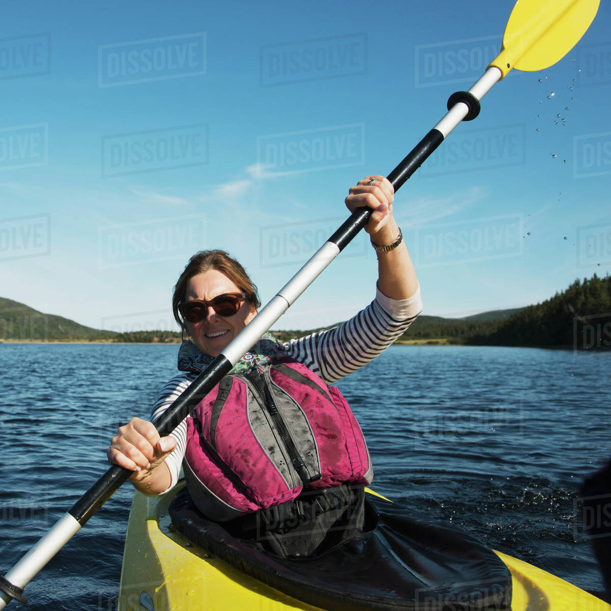 a woman with a paddle in a kayak in gros morne national park trout
