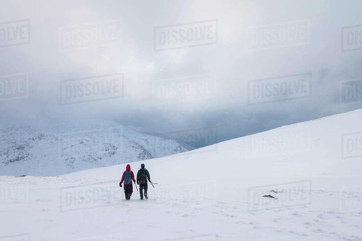Two people walking in snow covered, winter conditions on Beinn an