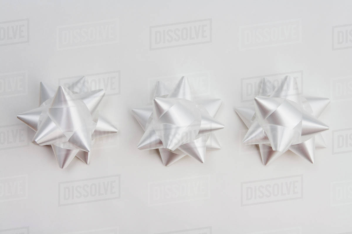 Three White Christmas Gift Bows In Row On White Background Studio