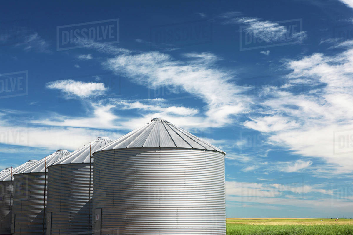 Metal Grain Bins With Blue Sky And Clouds South Of Cochrane; Alberta