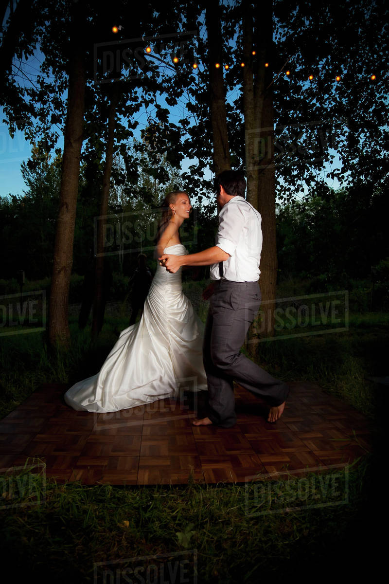 Bride And Groom Dancing At Dusk On An Illuminated Dance Floor