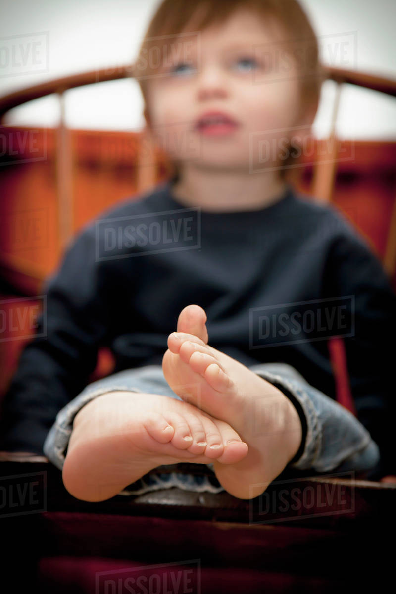 A Young Boy Sitting On A Chair With Bare Feet; Bellingham, Washington